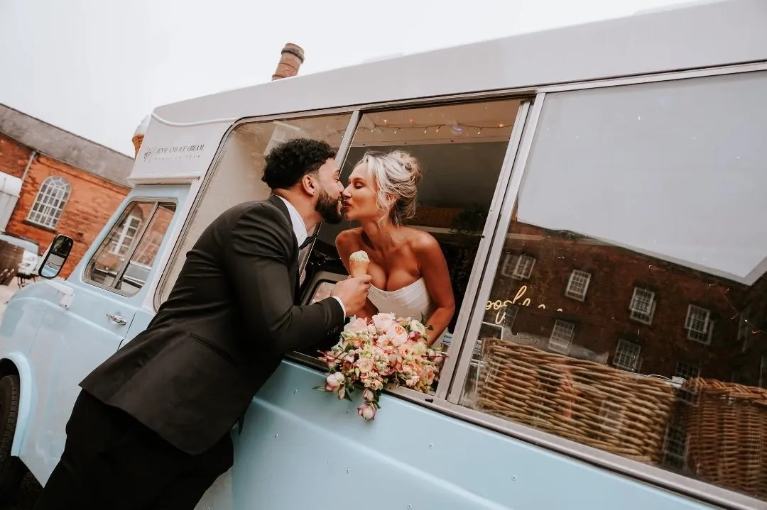 A newly married couple sharing a kiss and an ice cream at Sherpa’licious’s window